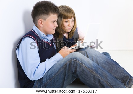 Boy and girl sitting on the floor. Boy showing something to girl on laptop. Side view.