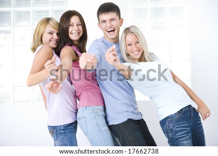 Four happy friends standing and snaping one\'s fingers. They\'re looking at camera.