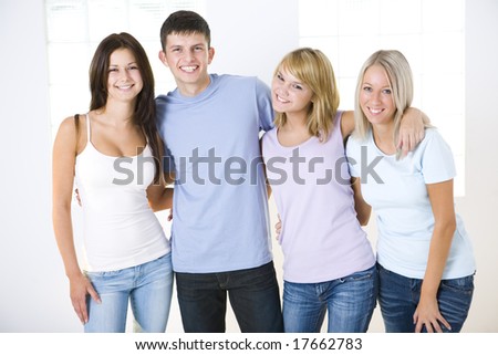 Group of young happy friends. They\'re standing and looking at camera. Front view.