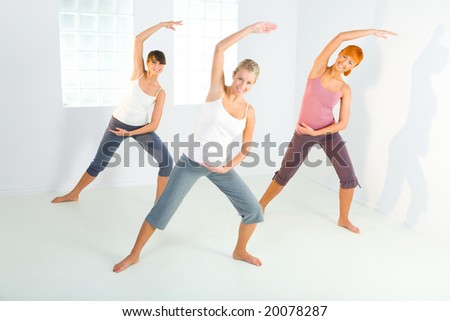 Group of women doing fitness exercise. They\'re looking at camera. Front view.