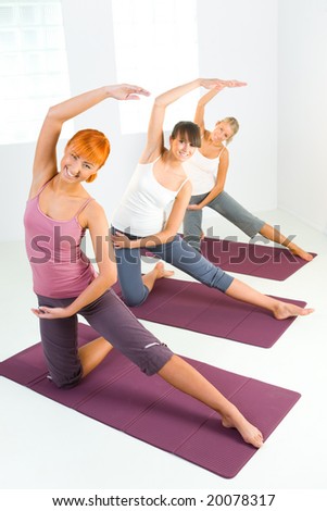 Group of women doing fitness exercise on mat. They're looking at camera.