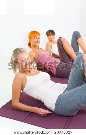 Group of women doing fitness exercise on mat. They\'re looking at camera.