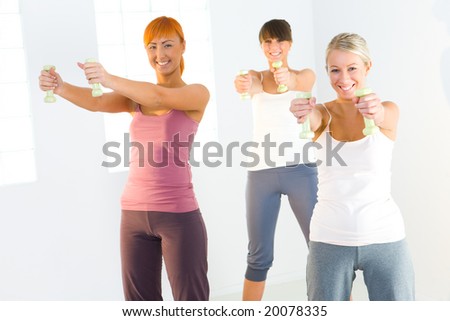 Group of women doing fitness exercise with dumbbells. They're looking at camera.
