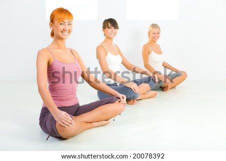 Three women sitting cross-legged on the floor and looking at camera.