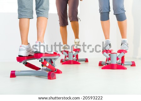 Group of women doing exercise on stepper. Closeup on legs. Low angle view.