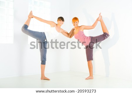 Two young women doing stretching exercises. They\'re looking at camera.