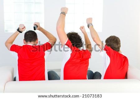 Three men sitting on couch with hands up. Rear view.