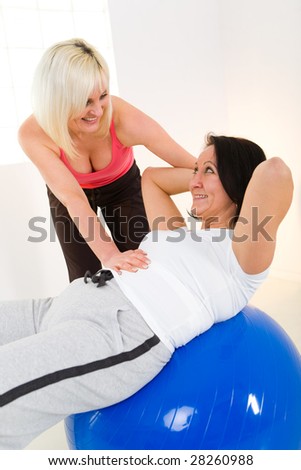 Elder woman dressed sportswear exercising abdominal muscles with her instructor.