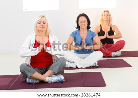 Elder women sitting cross-legged on mat and meditating