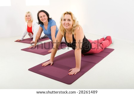 Elder women during exercising on mat. They\'re smiling and looking at camera.