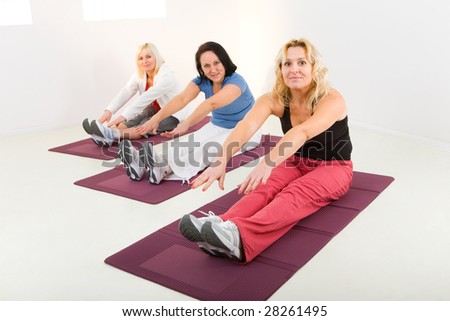 Elder women during exercising on mat. They\'re smiling and looking at camera.