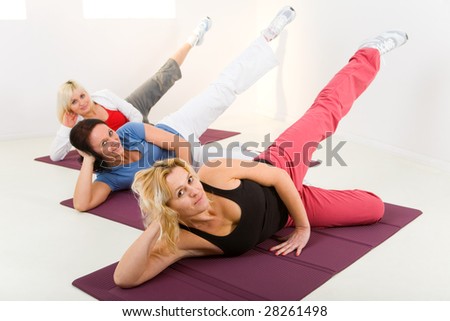 Elder women during exercising on mat. They're smiling and looking at camera.