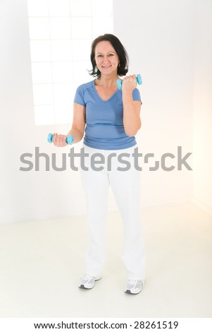 Elder woman exercising with dumbbell. She's smiling and looking at camera. Front viev.