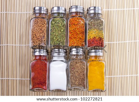 Eight jars of spices on the wooden background