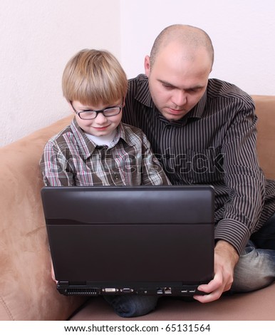 father son sitting on the couch with a computer
