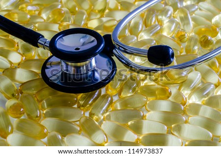 Closeup of stethoscope and fish oil capsules.  Concept showing heart health.