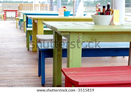 Colorful restaurant tables outside on terrace overlooking water.