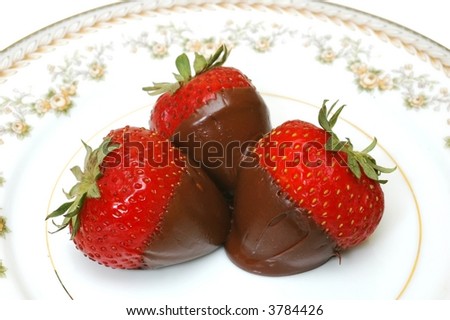 Three chocolate dipped  strawberries on plate.