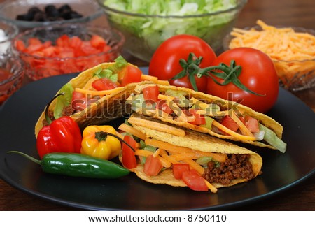 Prepared tacos with tomatoes, habanero and serrano peppers on plate.  Ingredients in background.