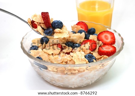 Breakfast cereal with strawberries and blueberries with orange juice in background.  Isolated on white background.