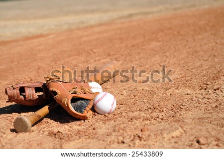 Baseballs, gloves, and bat on dirt infield with copy space.