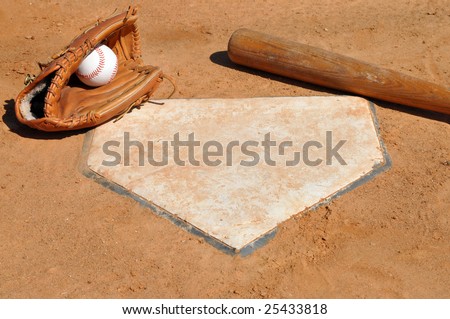 Baseball, glove, and bat on home plate.