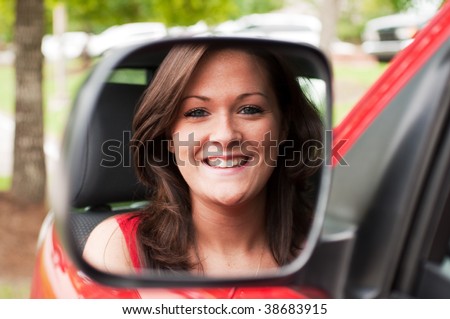 Female portrait of attractive brunette in vehicle mirror.