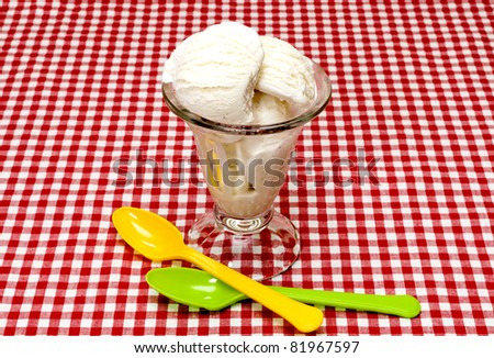 Vanilla ice cream and spoons on table with red gingham table cloth.