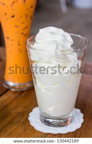One glass of whipped cream and iced tea with milk on background