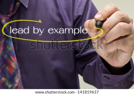 Businessman draw a circle mark on Lead By Example text