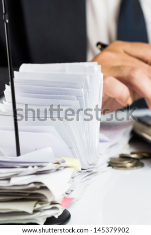 A lot of receipts in paper nail with accountant working on background