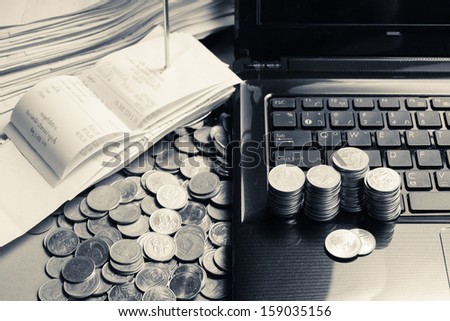 A lot of coins on laptop with receipts in paper nail