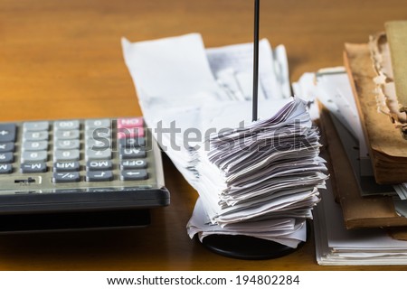 Bills in paper nail and pile of old books on wood table