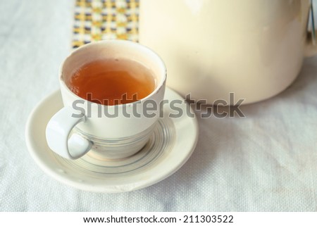 Small cup of tea on white wrinkled table cloth in retro style