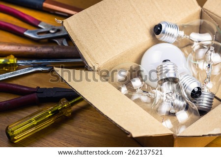 Many light bulbs in cardboard box with tools, change or improve idea concept