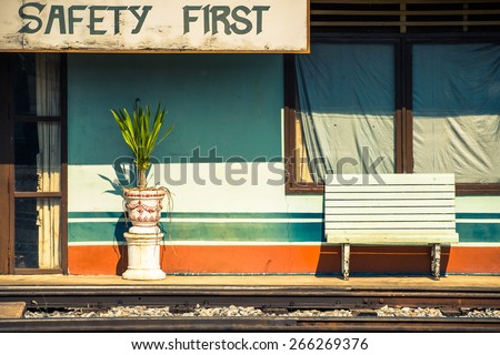 Old building with bench beside the railway with Safety First sign, train station in Thailand