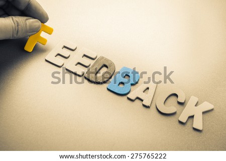 Hand arrange wood letters as Feedback word