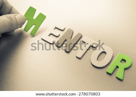 Hand arrange wood letters as Mentor word