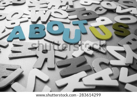 Color About Us word in scattered black and white wood letters