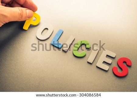 Hand arrange wood letters as Policies word