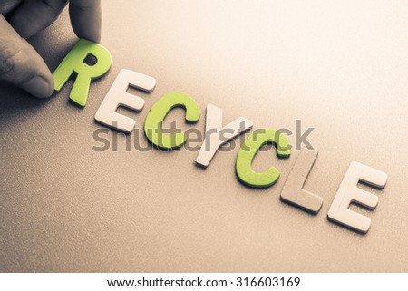 Hand arrange wood letters as Recycle word