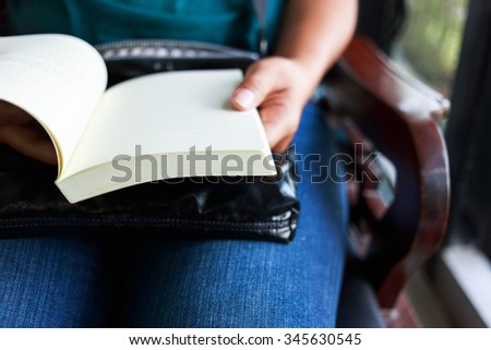 Closeup of a woman sitting on the chair and open book on her lap