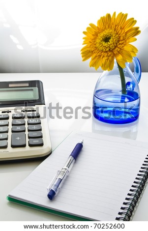 Business desk with bright yellow flower in blue vase