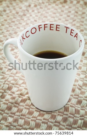White cup of black coffee on brown weaved cloth