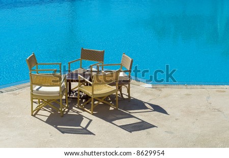 chairs and table on the edge of the swimming pool