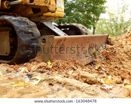 Excavator shovel pushing soil back into a hole