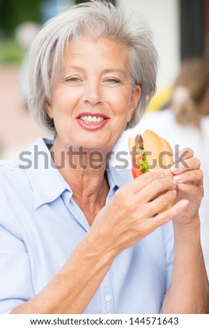 Smiling senior woman eating some fish