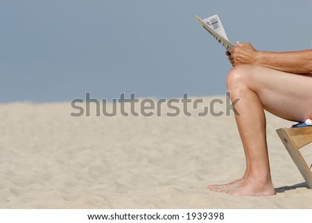 Older man with newspaper at the beach