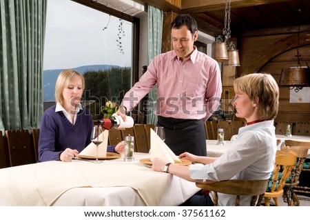 Waiter is serving some wine in a little restaurant