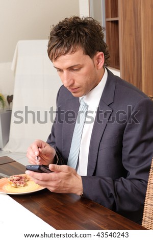Young businessman with his smartphone (cell) at the breakfast